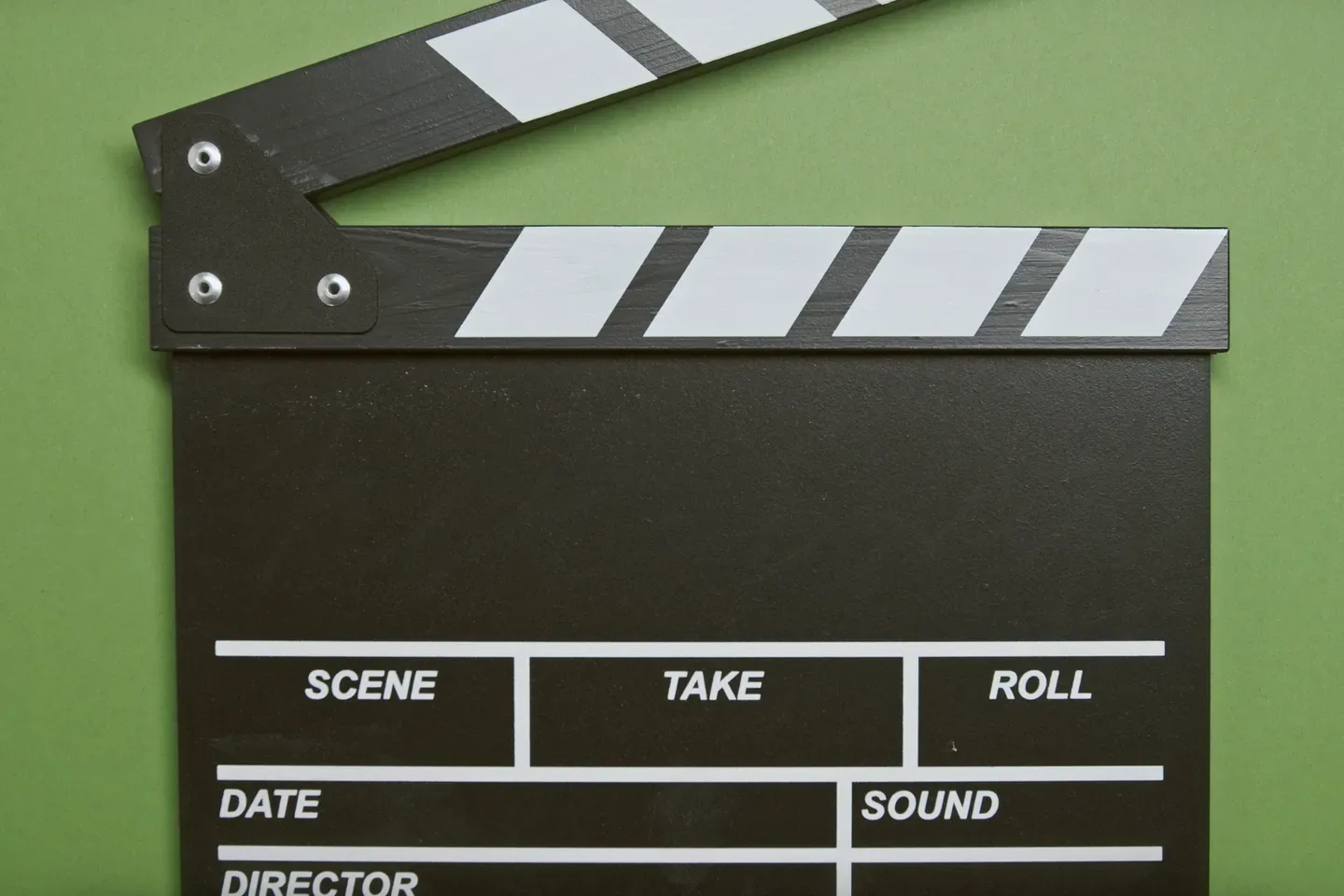A black film clapperboard with scene, take and roll fields on a green background