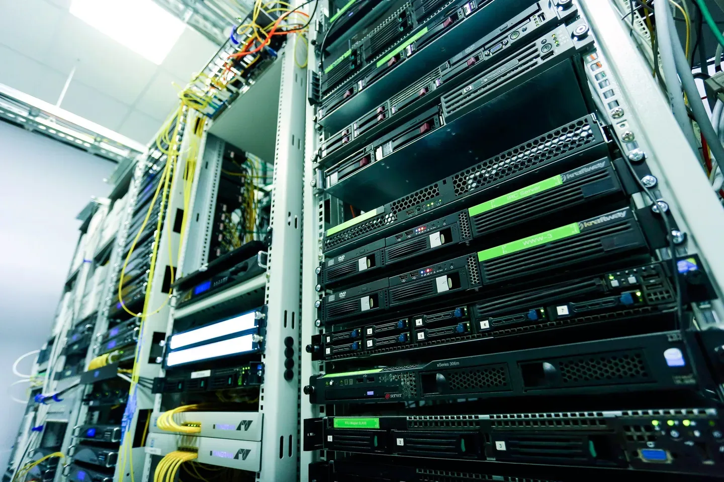 Rack-mounted servers with yellow fibre cables in a brightly lit data centre